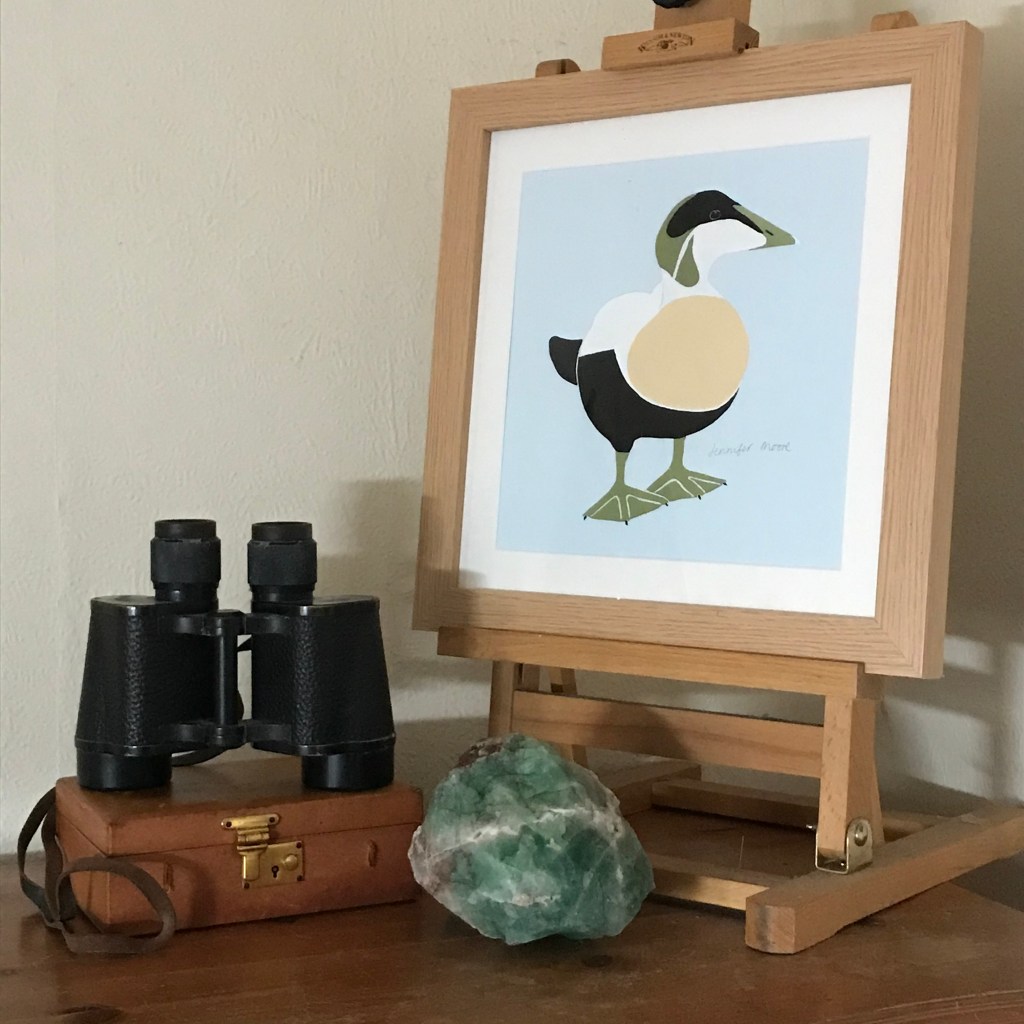 Painting of an Eider drake on an easel, with binoculars and a lump of quartz.